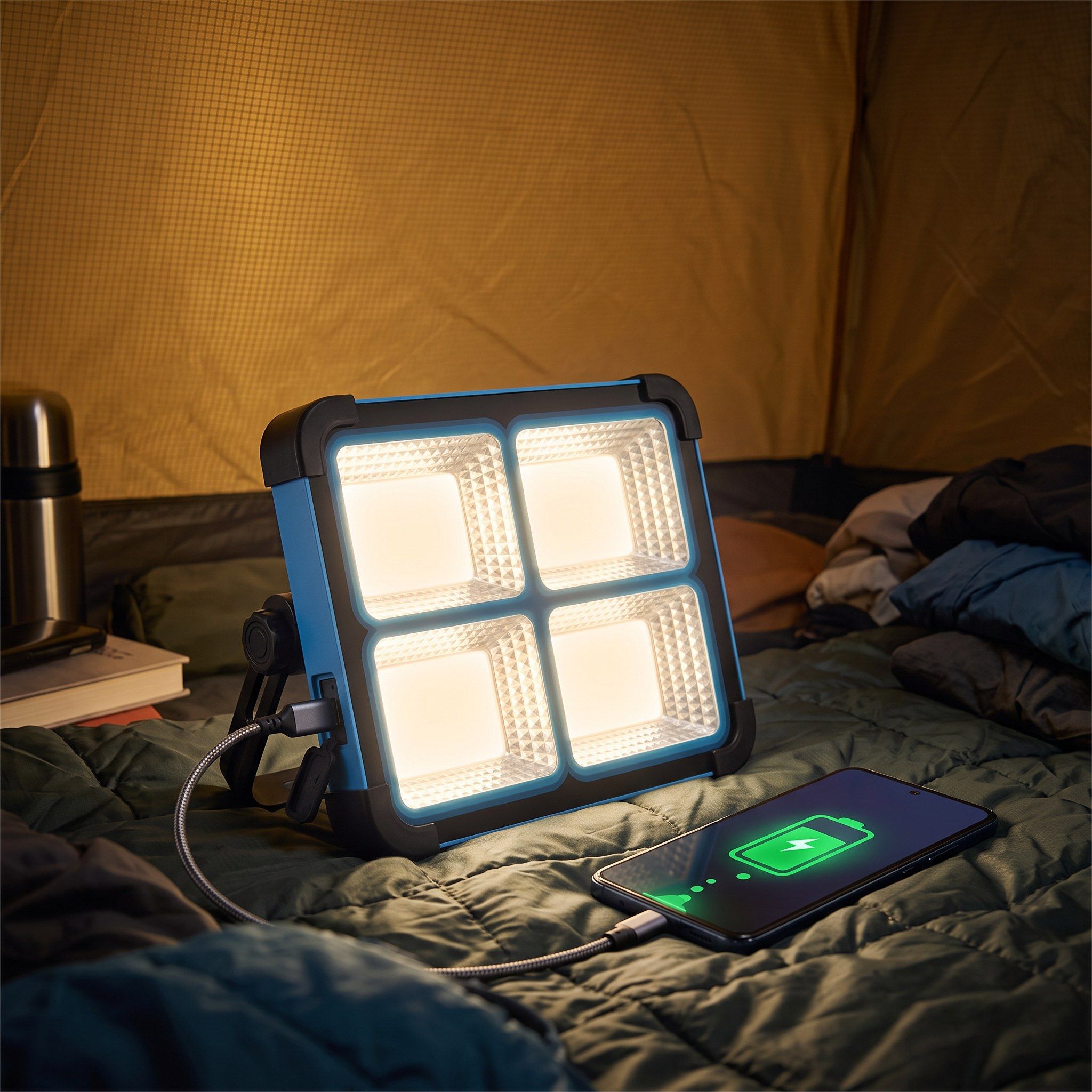 Solar LED work light charging a phone from its USB output in a tent